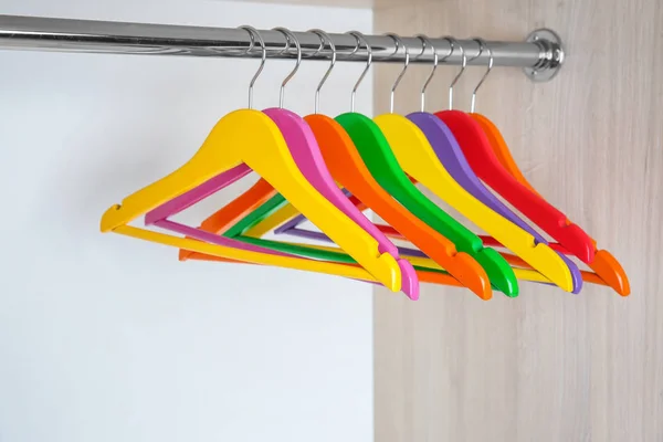 Colorful clothes hangers in empty wardrobe — Stock Photo, Image