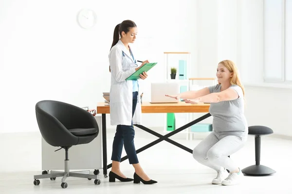 Νεαρή γυναίκα γιατρό παρατηρώντας υπέρβαρη γυναίκα κατά τη διάρκεια άσκησης στην κλινική — Φωτογραφία Αρχείου