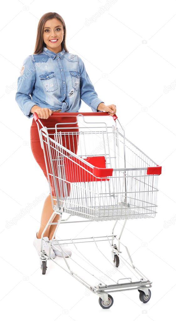 Young woman with empty shopping cart on white background