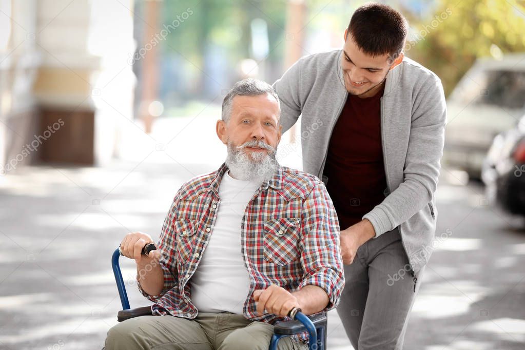 Young caregiver walking with senior man, outdoors