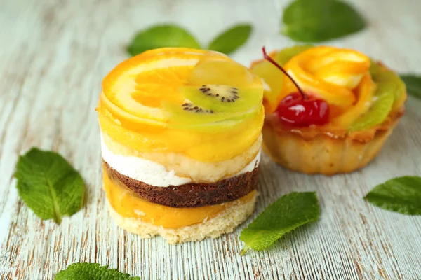 Tasty cakes with jelly fruits on wooden background