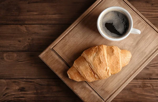 Deska s mňam čerstvý croissant a kafe na dřevěný stůl — Stock fotografie