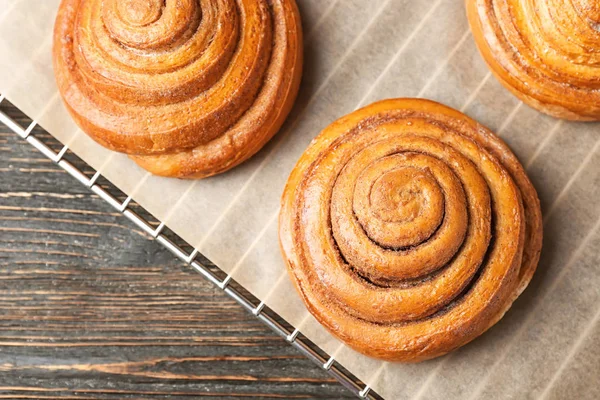 Cooling rack with sweet cinnamon rolls on table — Stock Photo, Image