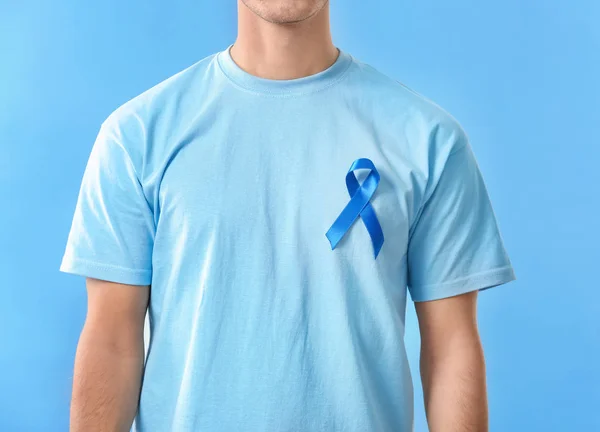 Mladý muž nosí tričko s modrou stuhou na barvu pozadí, closeup. Koncept povědomí o rakovině prostaty — Stock fotografie
