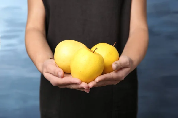 Mujer sosteniendo manzanas amarillas maduras sobre fondo de color —  Fotos de Stock