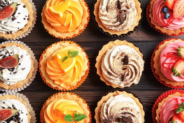Tasty colorful cakes on wooden background, top view — Stock Photo, Image