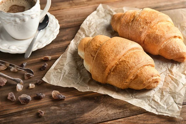 Deliciosos cruasanes frescos y una taza de café sobre una mesa de madera — Foto de Stock