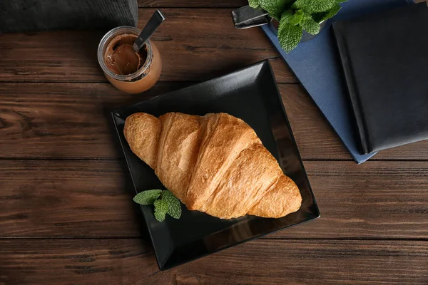 Placa com croissant fresco gostoso na mesa de madeira — Fotografia de Stock