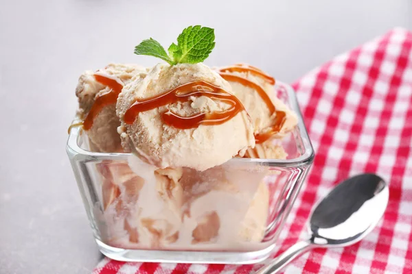 テーブルの上のガラスのボウルにキャラメルのトッピングでおいしいアイスクリーム — ストック写真