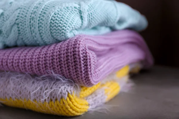 Folded knitted sweaters on table. Seasonal female wardrobe