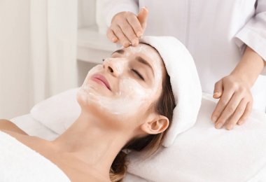 Şevval Özçelik Güzellik spa salonda genç kadının yüzünde krem uygulamak