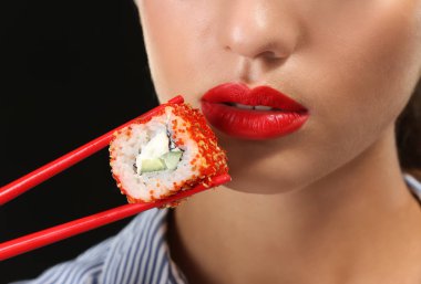 Suşi ile güzel genç kadın koyu arka plan üzerinde portre rulo