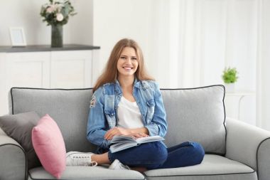 Güzel kadın evde koltukta istirahat ederken kitap okuma