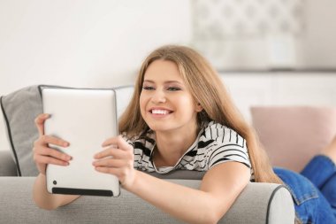 Güzel kadın evde koltukta istirahat ederken Tablet PC'yi kullanma