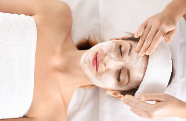 Şevval Özçelik Güzellik spa salonda genç kadının yüzünde krem uygulamak
