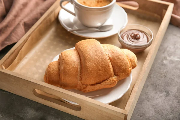 Bandeja com croissant gostoso e xícara de café na mesa — Fotografia de Stock