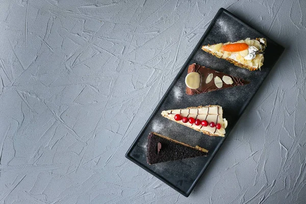 Deska s kousky chutné dorty na podklad s texturou — Stock fotografie