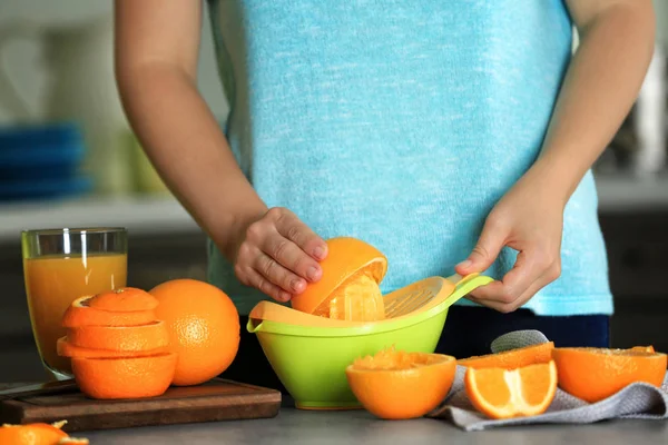 Mujer haciendo jugo de naranja en la cocina — Foto de Stock