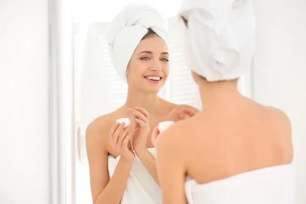 Mujer joven aplicando crema corporal — Foto de Stock