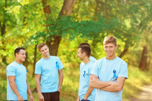 Mladý muž v tričku s modrou stužkou venku. Koncept povědomí o rakovině prostaty — Stock fotografie