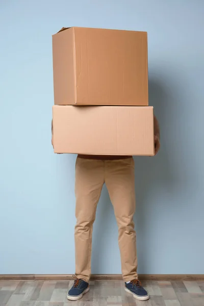 Man with moving boxes near color wall — Stock Photo, Image