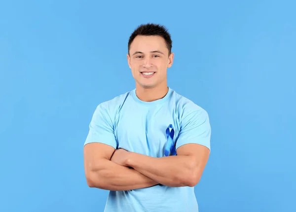 Jonge man dragen t-shirt met blauw lint op kleur achtergrond. Prostaatkanker bewustzijn concept — Stockfoto