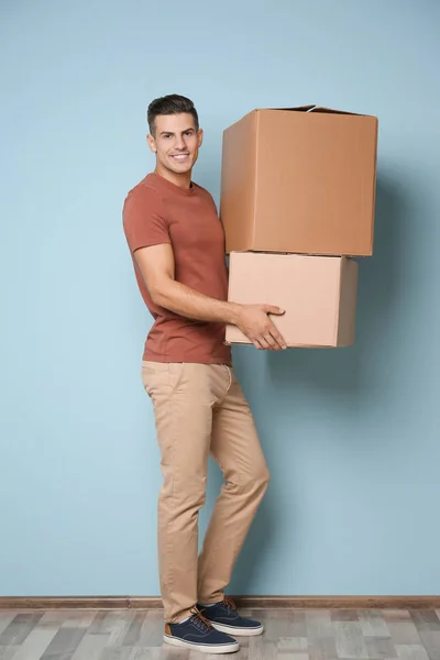 Man with moving boxes near color wall — Stock Photo, Image