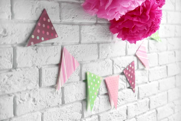 Fleurs artificielles et guirlande pour fête de douche de bébé sur mur de briques blanches — Photo