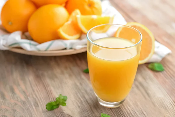 Vaso con delicioso jugo de naranja en la mesa —  Fotos de Stock