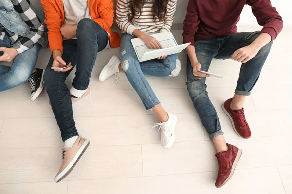 Група підлітків з сучасними пристроями сидить на підлозі — стокове фото