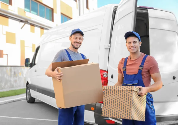 Delivery men with moving boxes near car — Stock Photo, Image