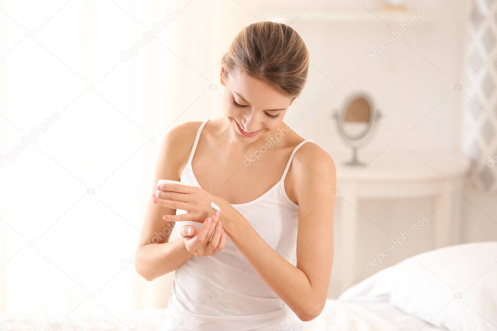 Young woman applying body cream  