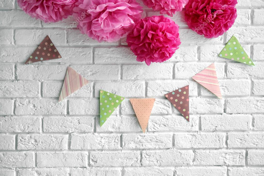 Artificial flowers and garland for baby shower party on white brick wall