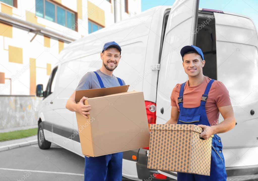 Delivery men with moving boxes near car