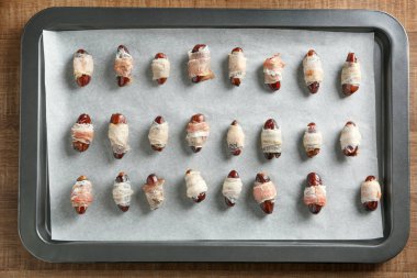 Pastırma ile fırın tepsisi tarihleri ahşap arka plan üzerinde sarılı.