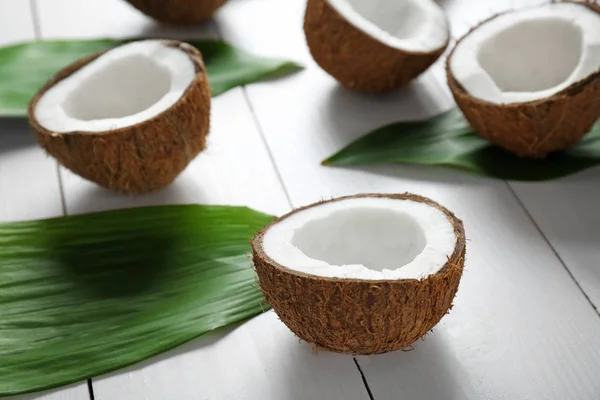 코코넛 반쪽과 나무 배경에 녹색 잎 — 스톡 사진