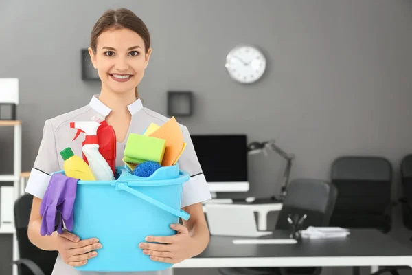 Junge Frau mit Putzutensilien im Büro — Stockfoto