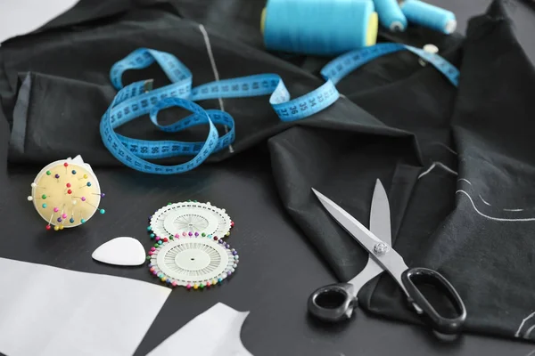 Tecido preto e acessórios de costura na mesa — Fotografia de Stock