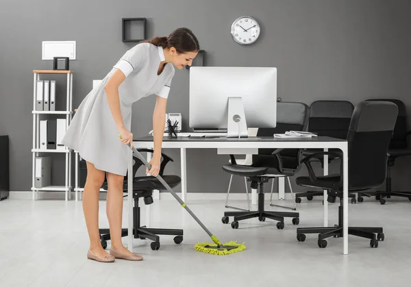 Mladá žena vytírání podlahy v úřadu — Stock fotografie