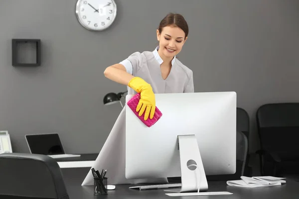 Mujer joven quitando polvo en la oficina — Foto de Stock