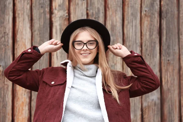 Attraktiva hipster flicka i hatt nära trästaket utomhus — Stockfoto