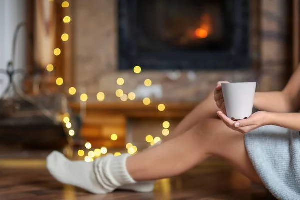 Mujer joven relajándose mientras bebe té en la sala de estar decorada para las vacaciones de invierno — Foto de Stock