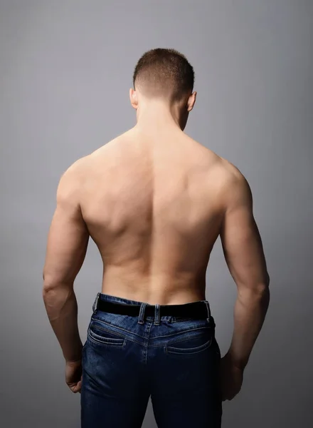 Muscular young bodybuilder on grey background