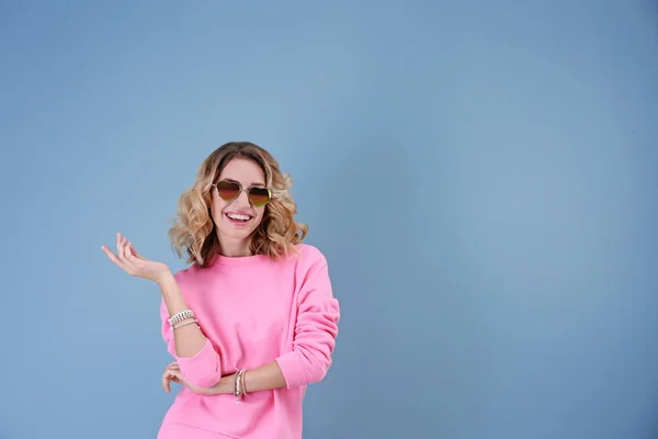 Attraente giovane donna con occhiali da sole a forma di cuore su sfondo di colore — Foto Stock