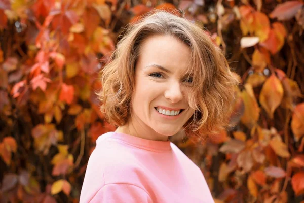 Hermosa mujer sonriente en sudadera rosa al aire libre —  Fotos de Stock