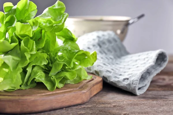 Bando de salada verde fresca e tábua de madeira na mesa — Fotografia de Stock