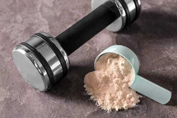 Protein tozu ve gri arka plan üzerinde halter ile ölçme Kepçe