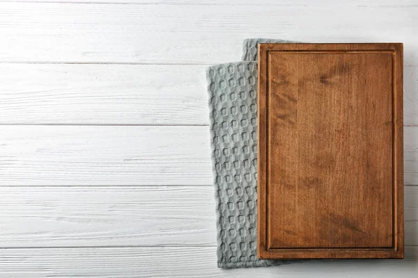 Sauberes Küchentuch und Brett auf weißem Holztisch, Draufsicht — Stockfoto