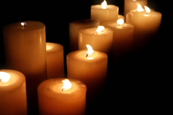 Muitas velas acesas no fundo escuro — Fotografia de Stock