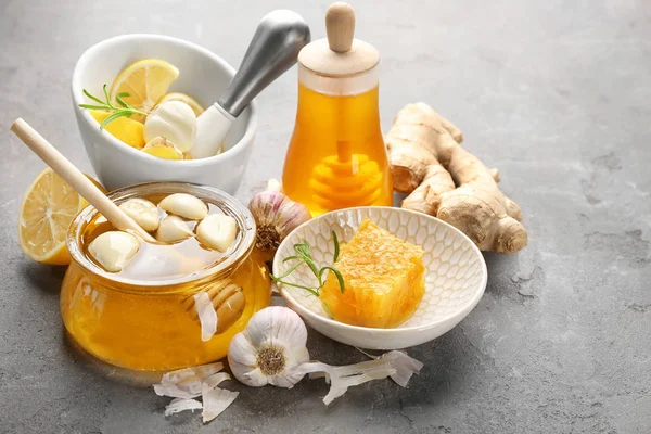 Samenstelling met honing en knoflook als natuurlijke koude remedies op grijs gestructureerde achtergrond — Stockfoto